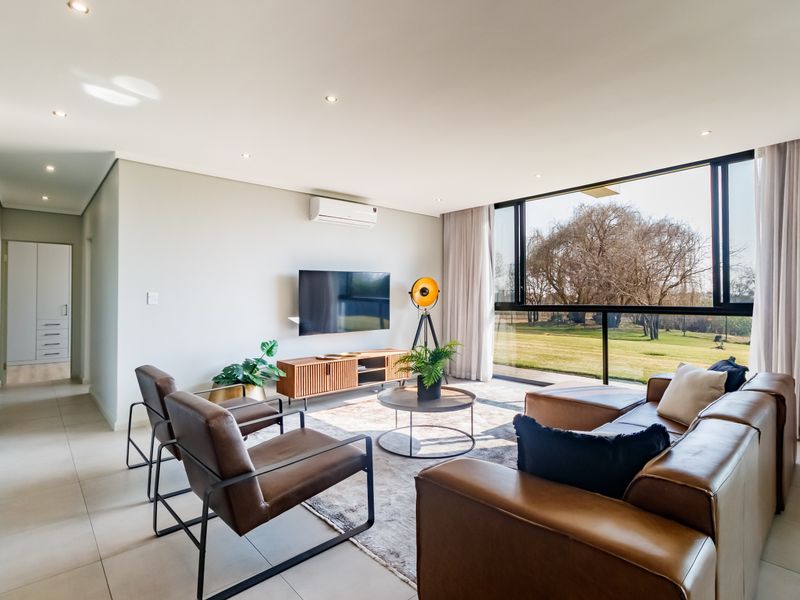 Modern, light-filled living room featuring tiled floors, recessed lighting, a split-system air conditioner, and large sliding glass doors with views of the garden.