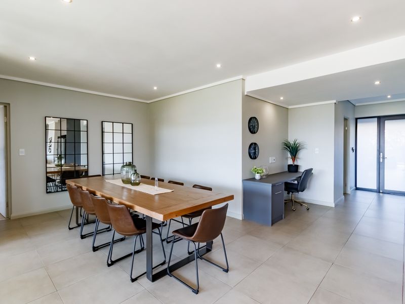 Spacious open-plan dining area featuring modern tiled flooring, recessed downlighting, and a convenient built-in study nook with a sleek desk.