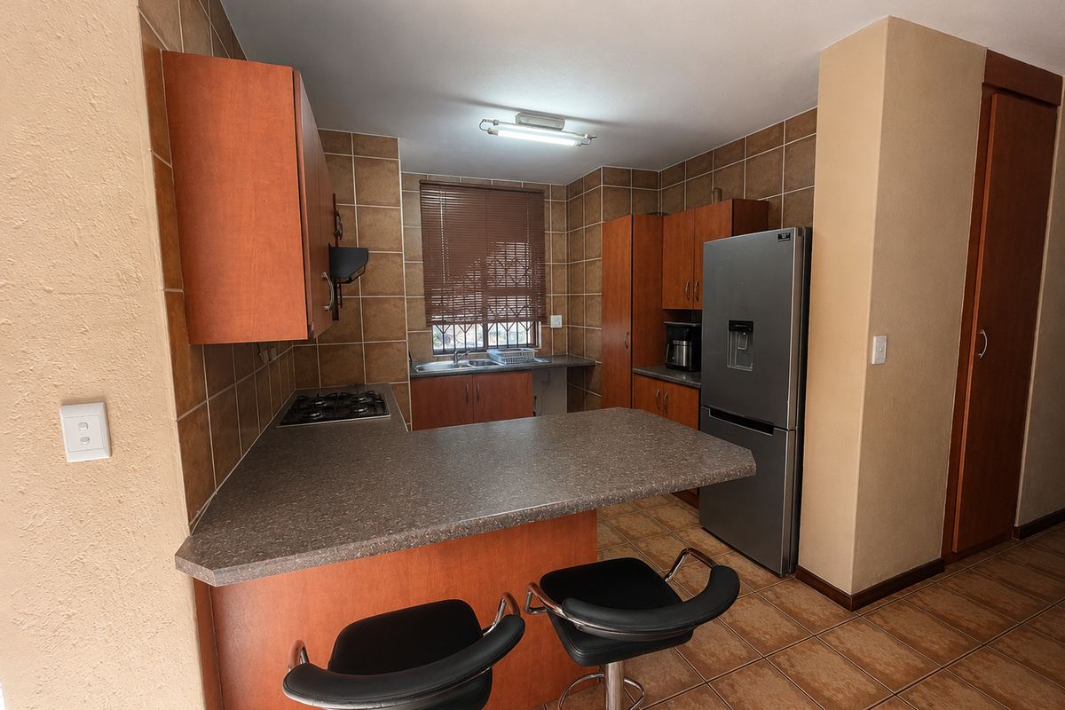 A functional kitchen featuring laminate cabinetry, tiled backsplash, gas hob, and a breakfast bar counter, providing a practical layout for daily meal preparation.
