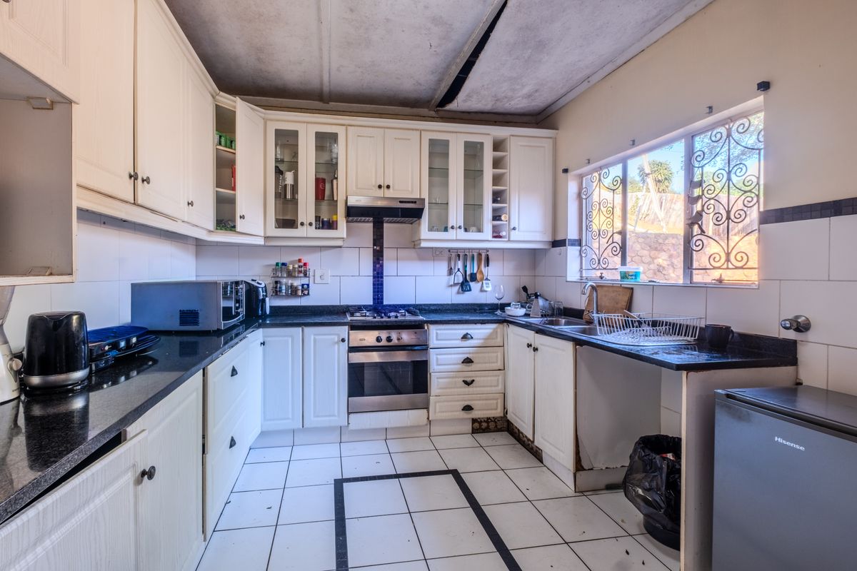 A functional kitchen featuring built-in cabinetry, granite countertops, and integrated appliances, requiring ceiling repairs and cosmetic updates to modernize the space.