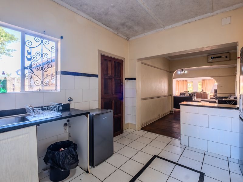 Kitchen area featuring tiled flooring, granite countertops, and a tiled splashback, leading through an archway into the adjacent living space.