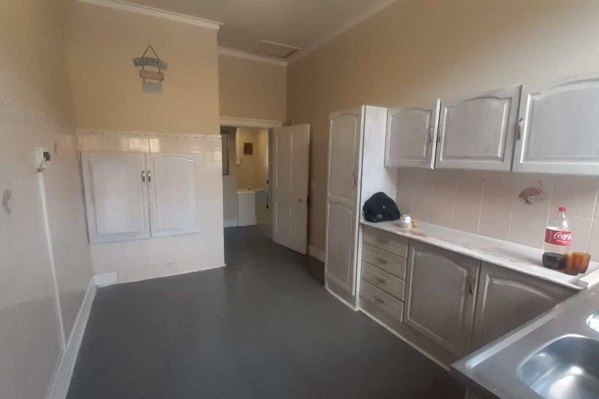 A dated kitchen featuring built-in cabinetry, a double bowl stainless steel sink, and tiled splashbacks, offering potential for a modern renovation.