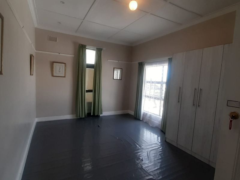 A spacious, empty bedroom featuring built-in cupboards, a classic panelled ceiling, and picture rails, offering a blank canvas for personalization.