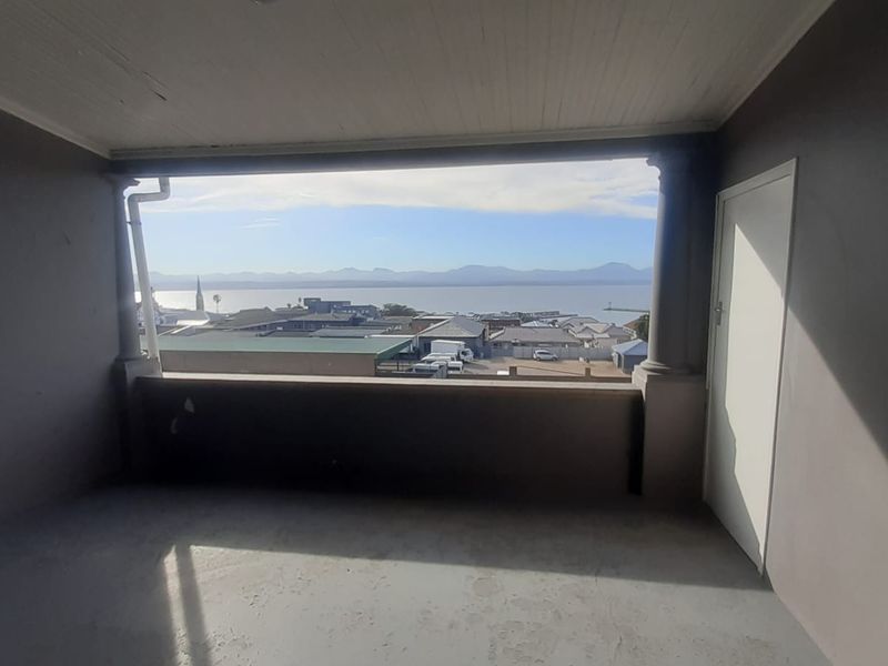 Covered balcony featuring a concrete floor, structural columns, and expansive coastal and mountain views.
