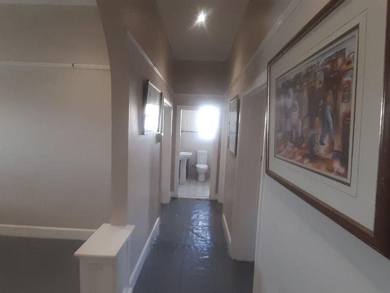 A hallway leading to a bathroom, featuring neutral wall tones, picture rails, and recessed lighting, with a view of the adjacent bathroom fixtures.