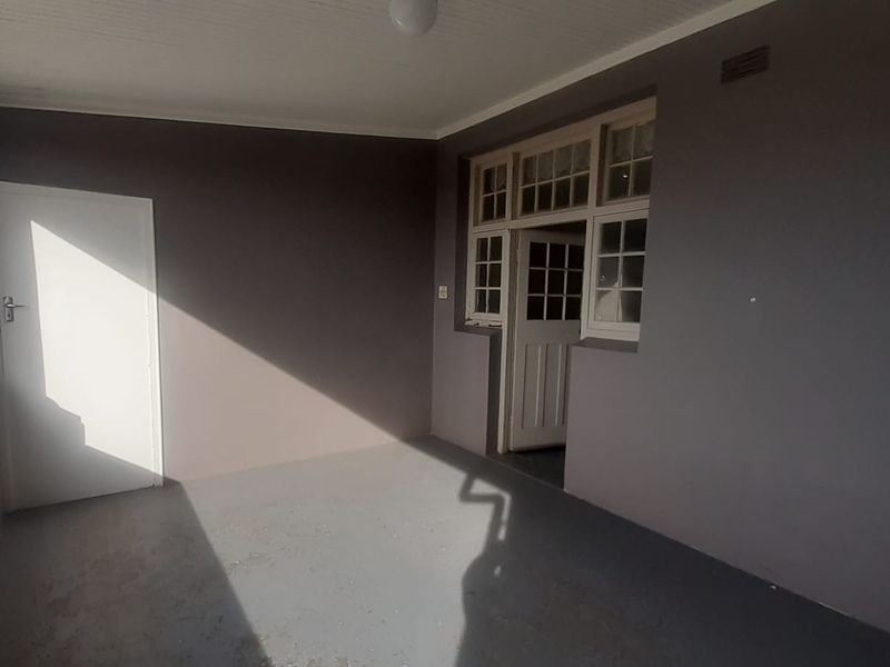 A covered balcony area featuring painted concrete flooring, a structural column, and access to the interior through a multi-pane door and window assembly.
