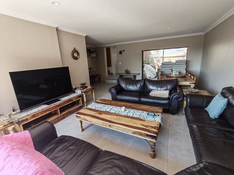Spacious open-plan living and dining area featuring neutral wall tones, tiled flooring, and large sliding glass doors providing natural light and garden access.