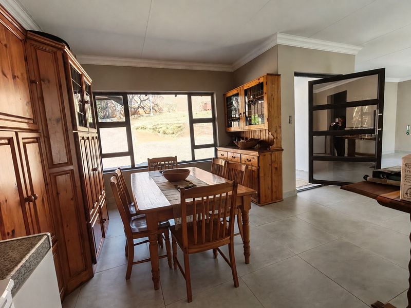 A dining room featuring tiled flooring, crown molding, and built-in wooden cabinetry, with a large window providing natural light.