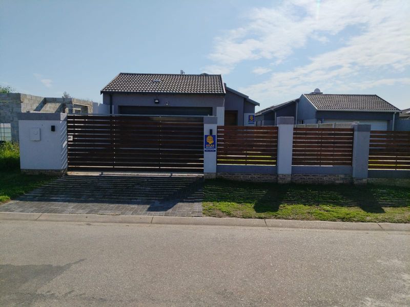 Front elevation of a modern residential property featuring a secure sliding gate, timber slat fencing, and a paved driveway.