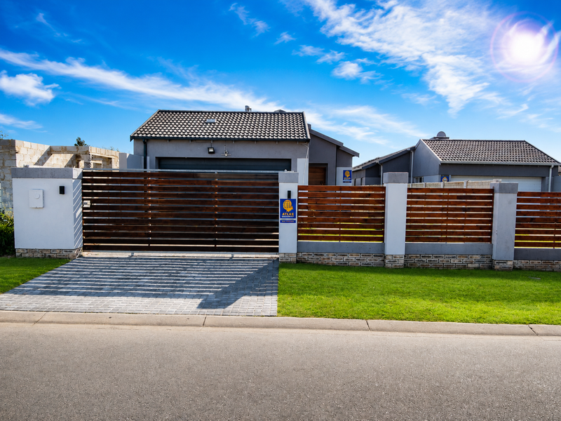 Front elevation of a modern house featuring a horizontal timber slat fence, concrete pillars, paved driveway, and a tiled roof.