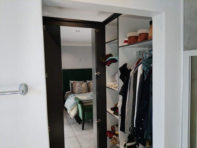 A view through a doorway into a bedroom featuring tiled floors, recessed lighting, and a built-in wardrobe with shelving and hanging space.