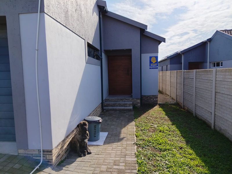 Front entrance view of the house featuring a paved walkway, timber front door, and a precast concrete boundary wall.