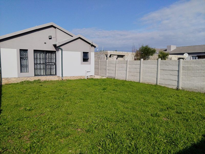 Rear view of the property featuring a private garden, a precast concrete boundary wall, and a sliding door entrance.