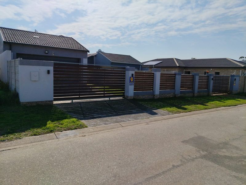 Front view of the property featuring a modern horizontal slat fence, concrete pillars, and a paved driveway leading to the garage.