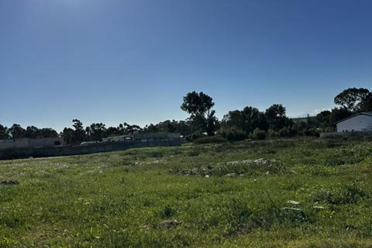 A vacant residential plot of land featuring open grass areas and boundary fencing, suitable for future development.