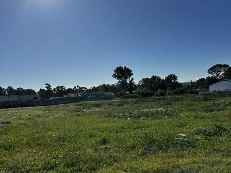 A vacant residential plot of land featuring open grass areas and boundary fencing, suitable for future development.