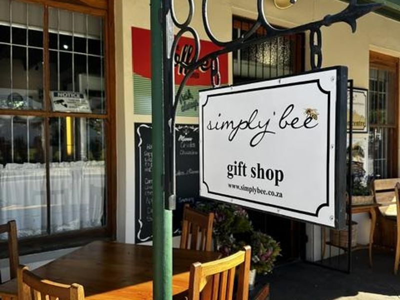 A covered patio area featuring a decorative wrought iron signage bracket and timber-framed windows, providing an inviting entrance to the commercial space.