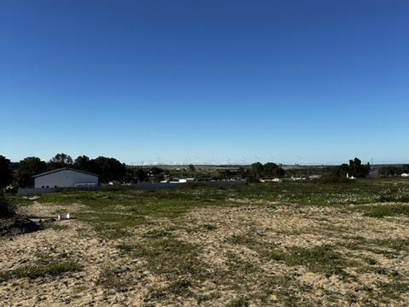 A view of a vacant residential plot of land with natural ground cover and distant horizon views.