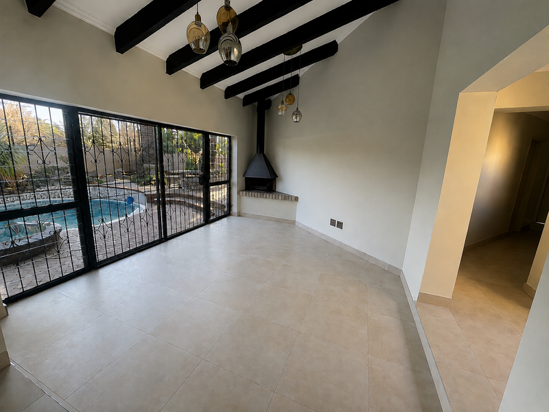 Spacious living area featuring exposed timber ceiling beams, a corner fireplace, and large sliding doors providing direct access to the pool area.