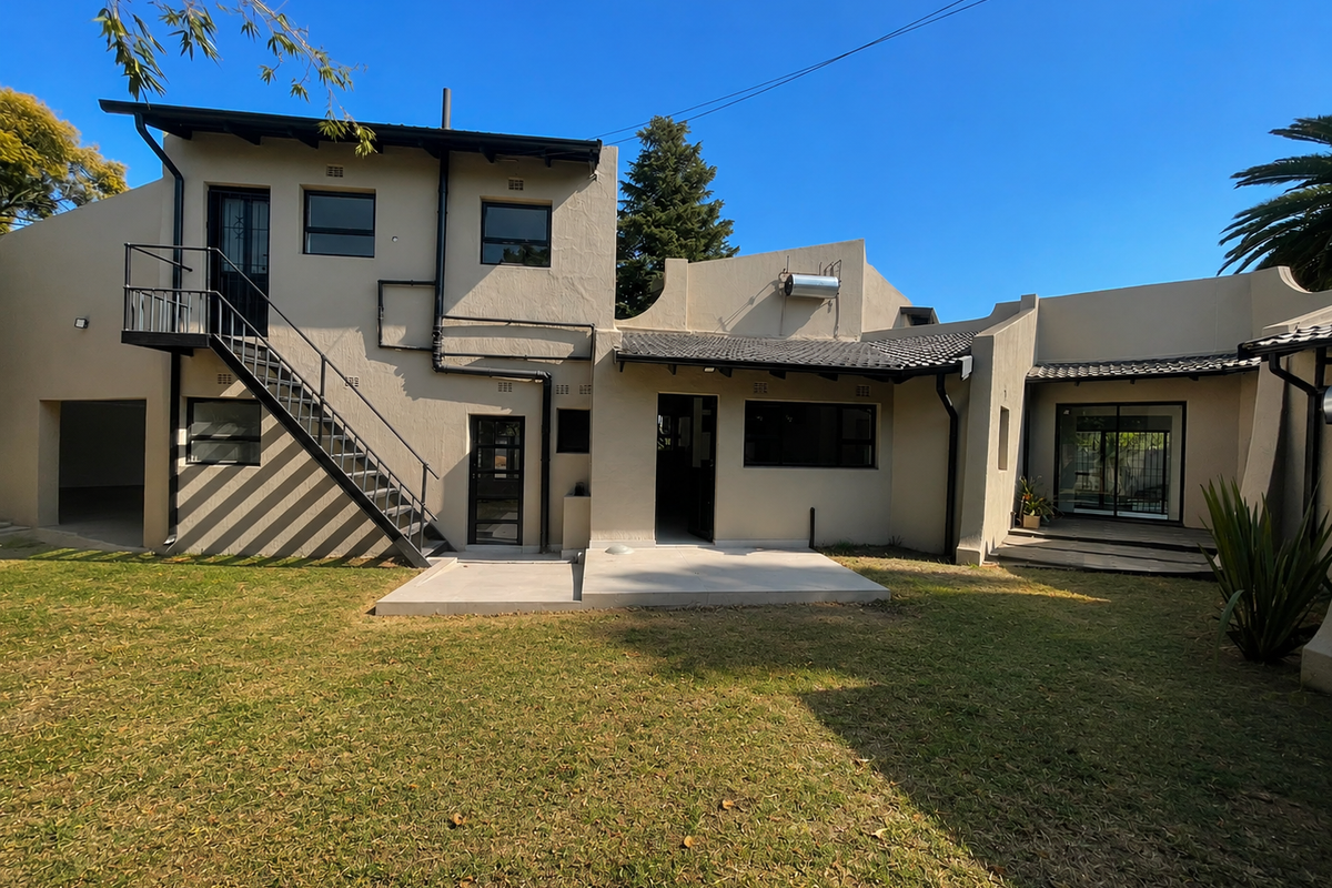 Rear view of the property featuring a multi-level exterior design, external staircase, solar water heater, and a paved patio area leading to the garden.