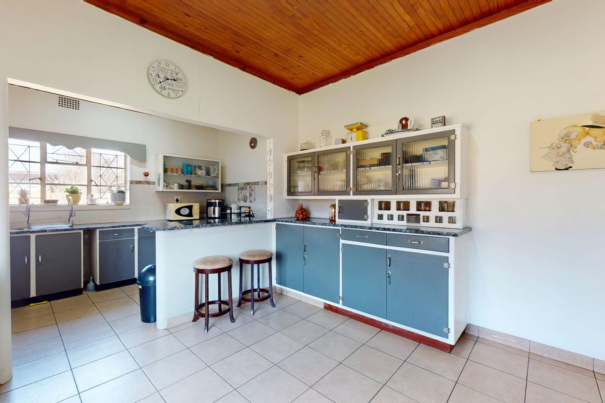 A functional kitchen featuring built-in cabinetry, laminate countertops, a double sink, and a timber-clad ceiling, offering a classic layout with potential for modernization.
