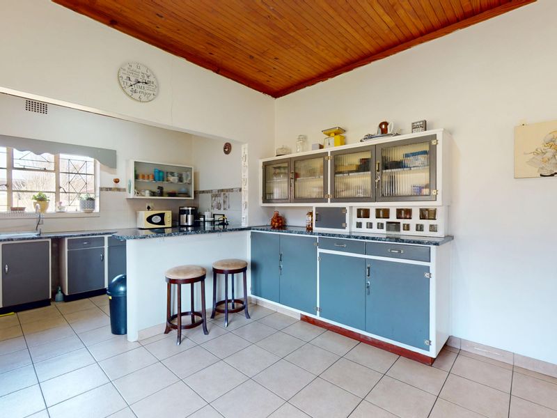 A functional kitchen featuring built-in cabinetry, laminate countertops, a double sink, and a timber-clad ceiling, offering a classic layout with potential for modernization.