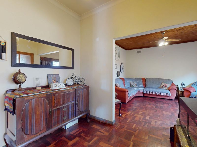 Open-plan living area featuring traditional parquet flooring and a timber-clad ceiling with a central fan, creating a warm and connected living space.