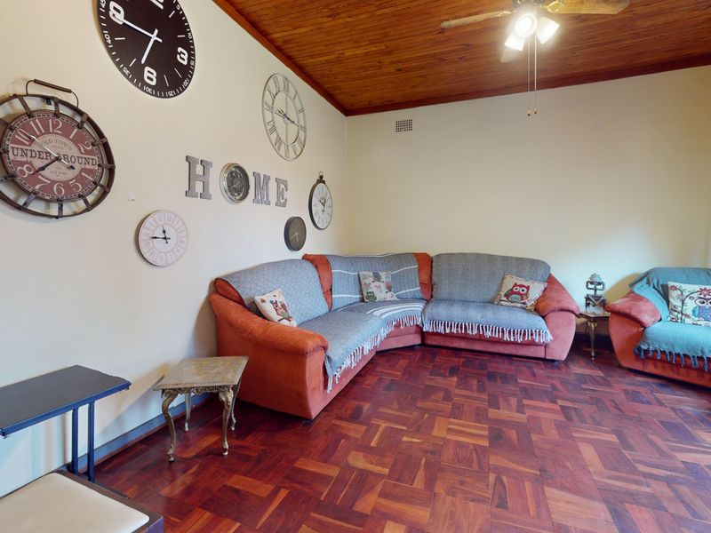 A living room featuring warm parquet flooring and a traditional timber-paneled ceiling with an integrated fan.