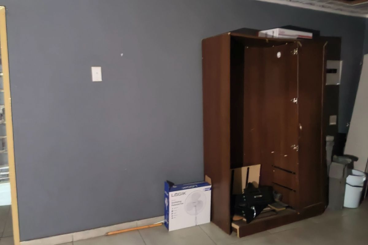 A bedroom space featuring tiled flooring and dark grey walls, currently requiring maintenance and finishing touches to the ceiling and adjacent wall areas.