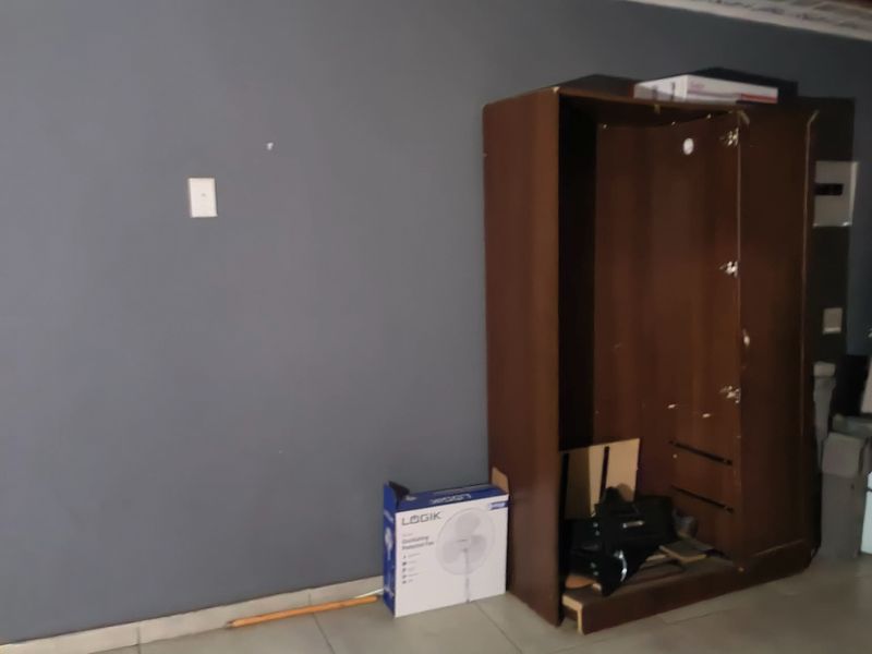 A bedroom space featuring tiled flooring and dark grey walls, currently requiring maintenance and finishing touches to the ceiling and adjacent wall areas.