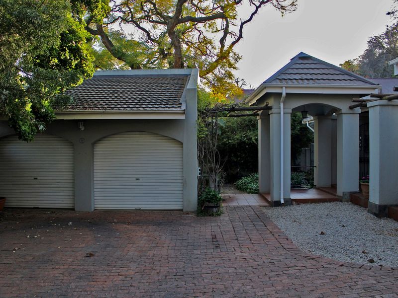 Front exterior view featuring a double garage with roller doors and a covered entrance walkway with tiled flooring and structural pillars.