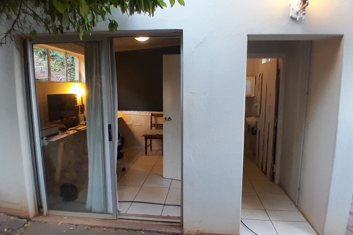 Exterior view of a rear patio area featuring a sliding glass door entrance to an interior room and a separate doorway.