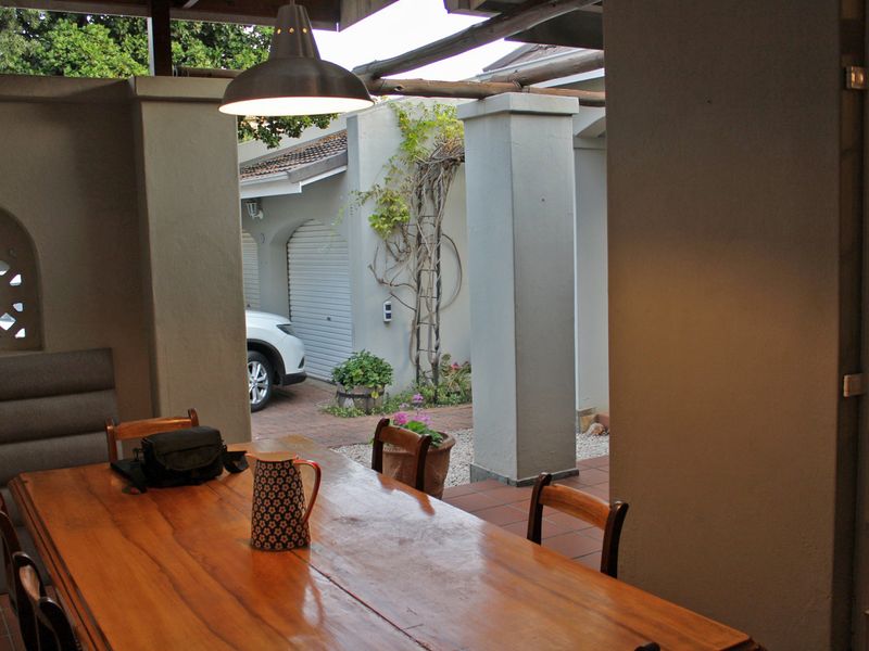 A covered outdoor patio area featuring tiled flooring, concrete pillars, and a decorative arched wall, providing a functional space for outdoor dining.