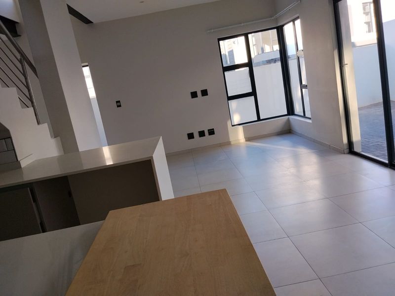 An open-plan living area featuring modern tiled flooring, a kitchen island, and large sliding doors leading to an outdoor space.