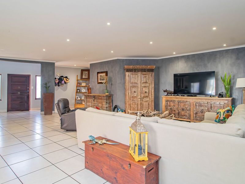 Spacious open-plan living area featuring neutral tiled flooring, recessed downlighting, and a distinctive dark feature wall.