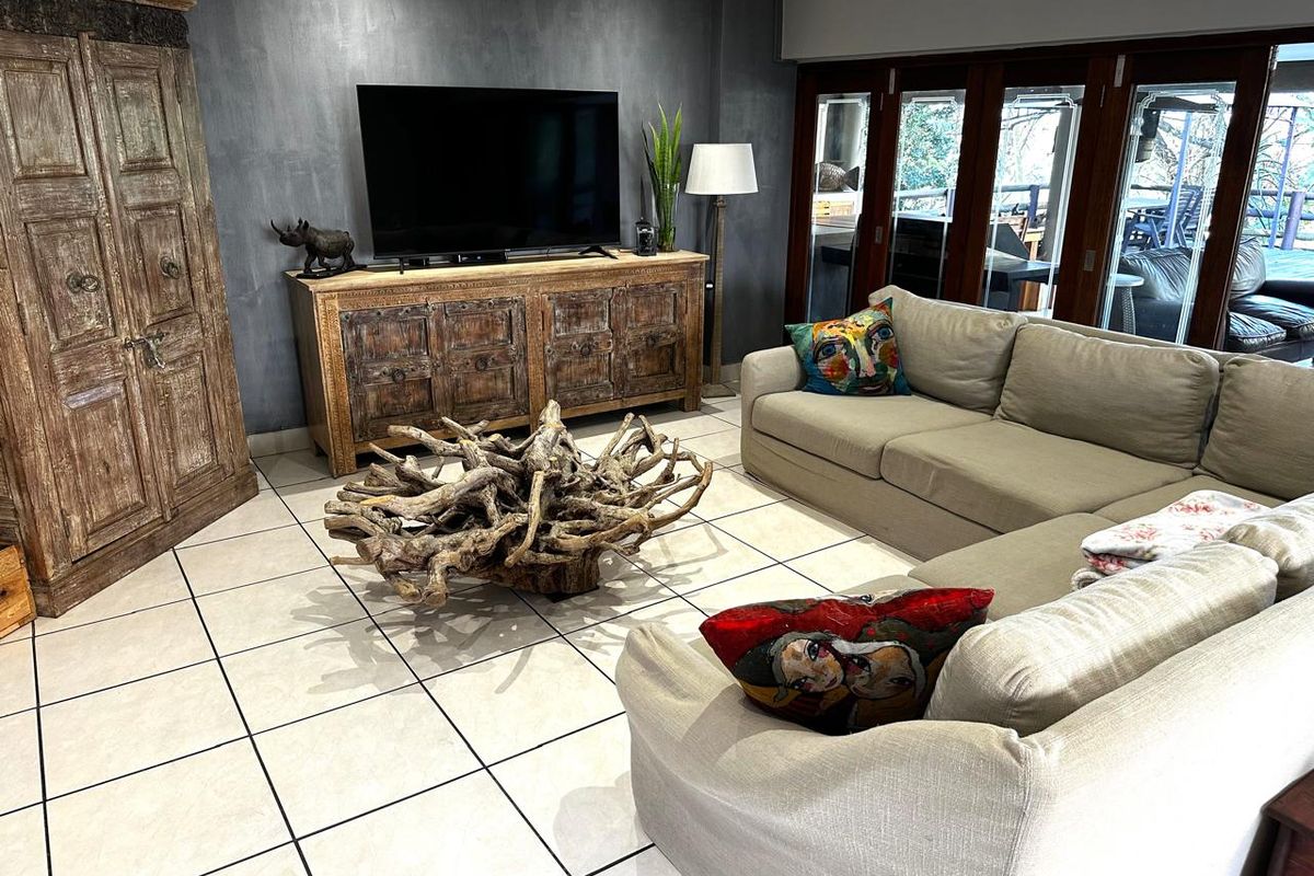 Spacious living room featuring large format floor tiles, a dark feature wall, and bi-fold doors providing seamless access to the outdoor area.