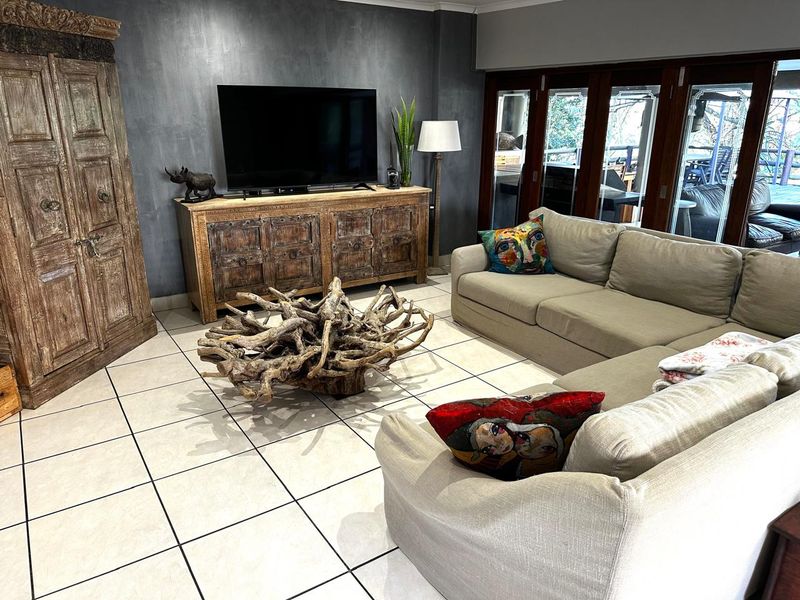 Spacious living room featuring large format floor tiles, a dark feature wall, and bi-fold doors providing seamless access to the outdoor area.