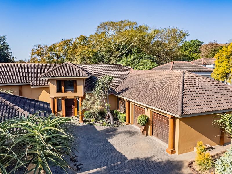 An elevated view of the front facade featuring a tiled roof, paved driveway, and double garage entrance.