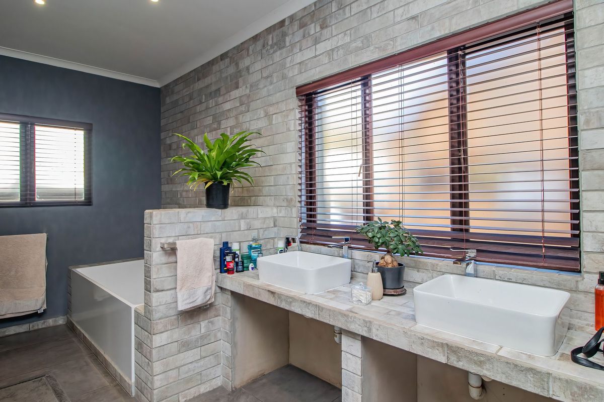 Modern bathroom featuring a double vanity with vessel sinks, built-in brick base, and a separate bathtub with contemporary finishes.