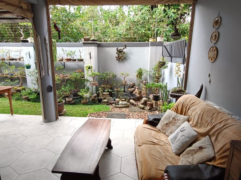A covered patio area featuring tiled flooring, seamlessly transitioning into a landscaped garden space with boundary walls.