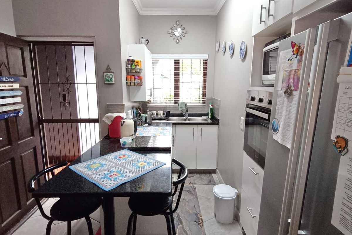 Compact kitchen featuring granite countertops, built-in oven, microwave, and ample cabinetry, with direct access to an exterior security gate.