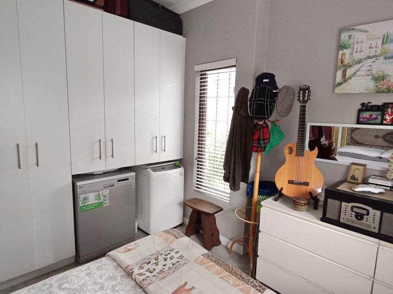 Bedroom featuring extensive built-in cupboard storage and a window with fitted venetian blinds.