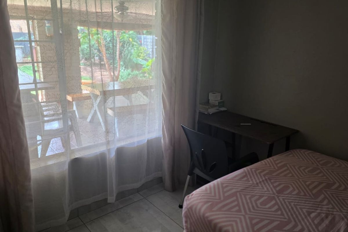 A bedroom featuring tiled flooring and a large window with direct access to an outdoor patio area.