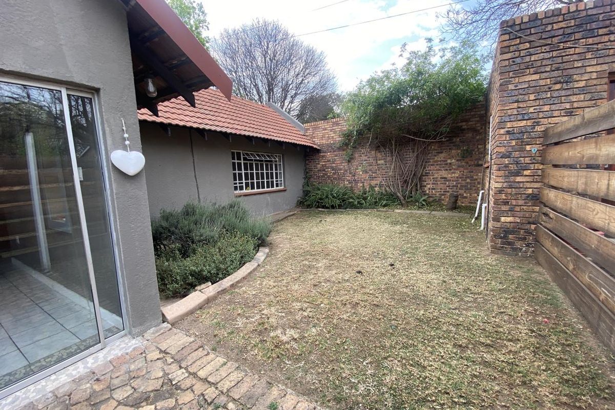 A private rear garden featuring a paved patio area, brick boundary walls, and a sliding door entrance to the cottage interior.