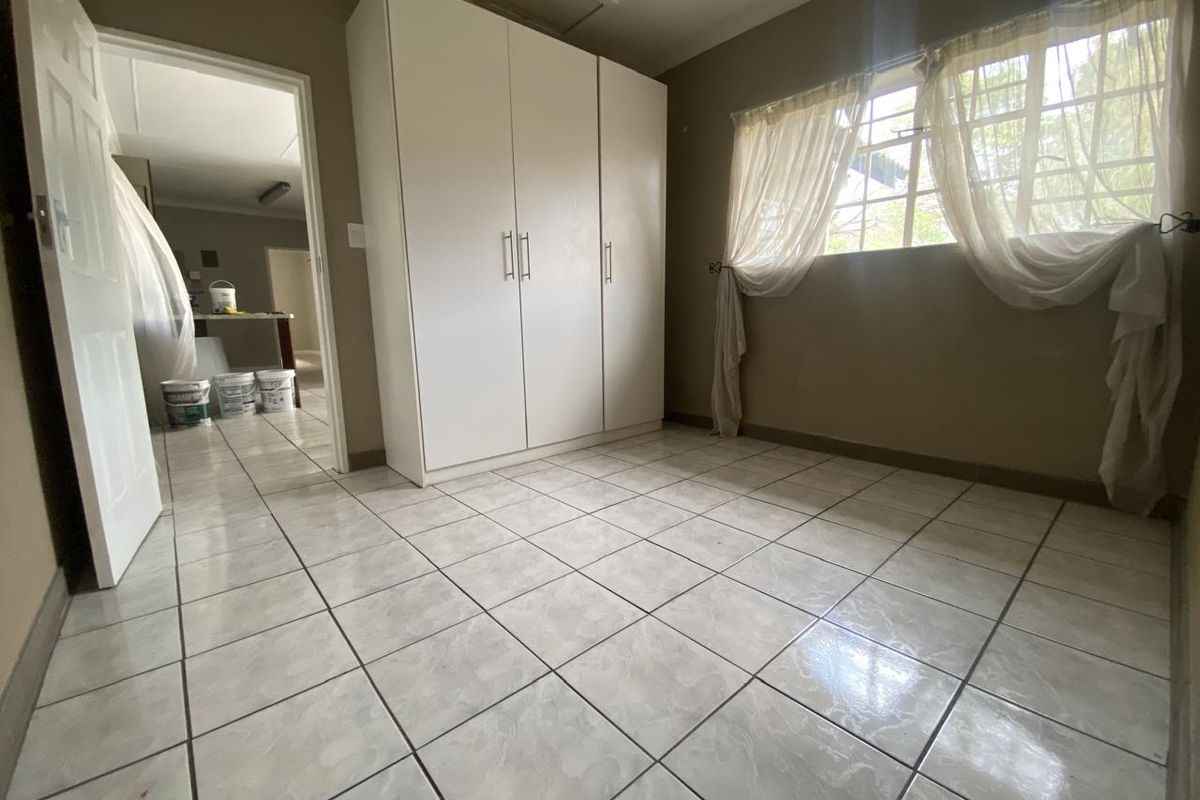 A bright, empty bedroom featuring tiled flooring and a built-in wardrobe, offering a clean canvas for personalization.