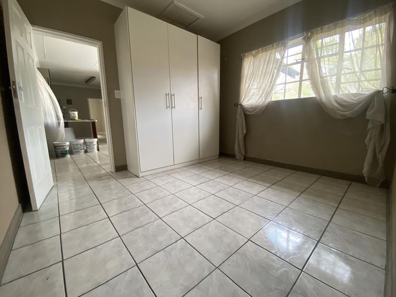 A bright, empty bedroom featuring tiled flooring and a built-in wardrobe, offering a clean canvas for personalization.