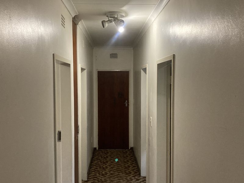 A functional hallway featuring neutral walls, carpeted flooring, and multiple internal door access points.