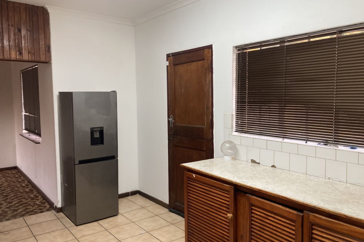 Kitchen area featuring wooden cabinetry, tiled flooring, and a tiled backsplash, requiring cosmetic updates to modernize the space.