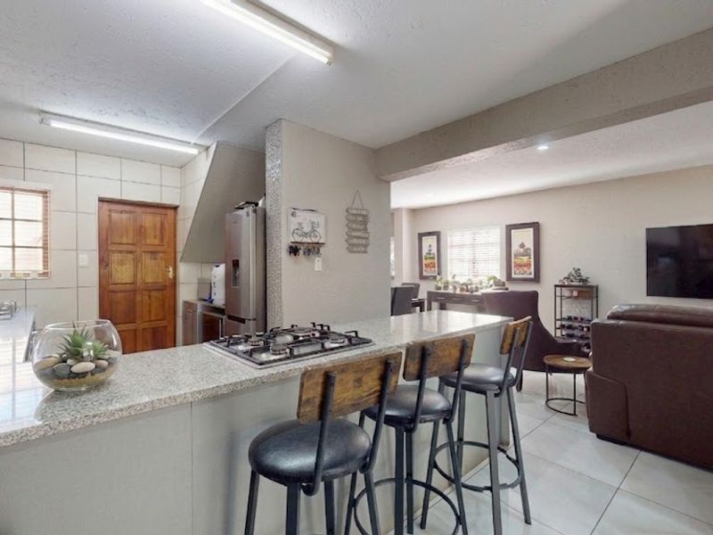 Open-plan kitchen and living area featuring granite countertops, a gas hob, and tiled flooring, creating a functional and connected living space.