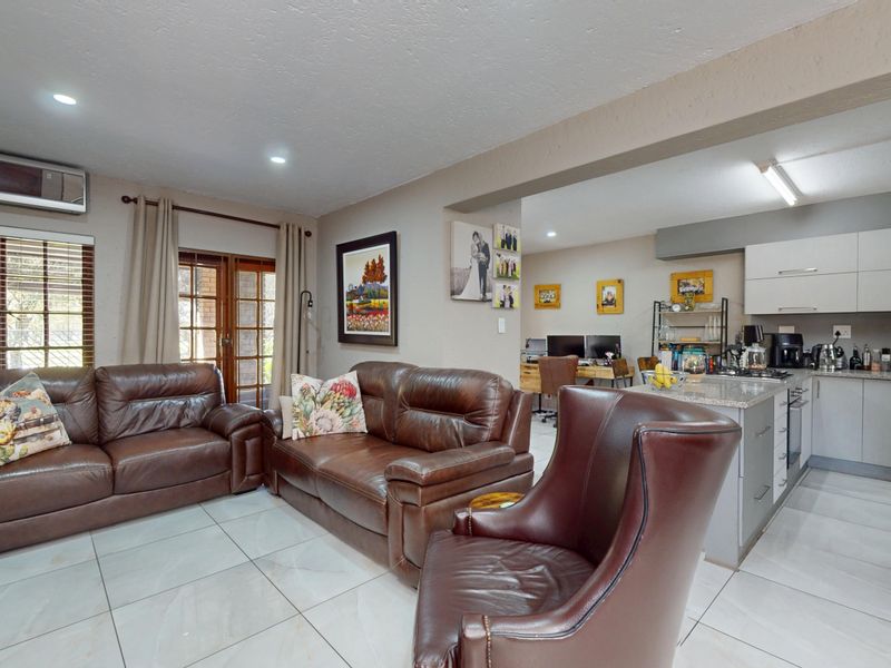 Spacious open-plan living area featuring modern tiled floors, recessed lighting, and a contemporary kitchen with stone countertops and integrated appliances.